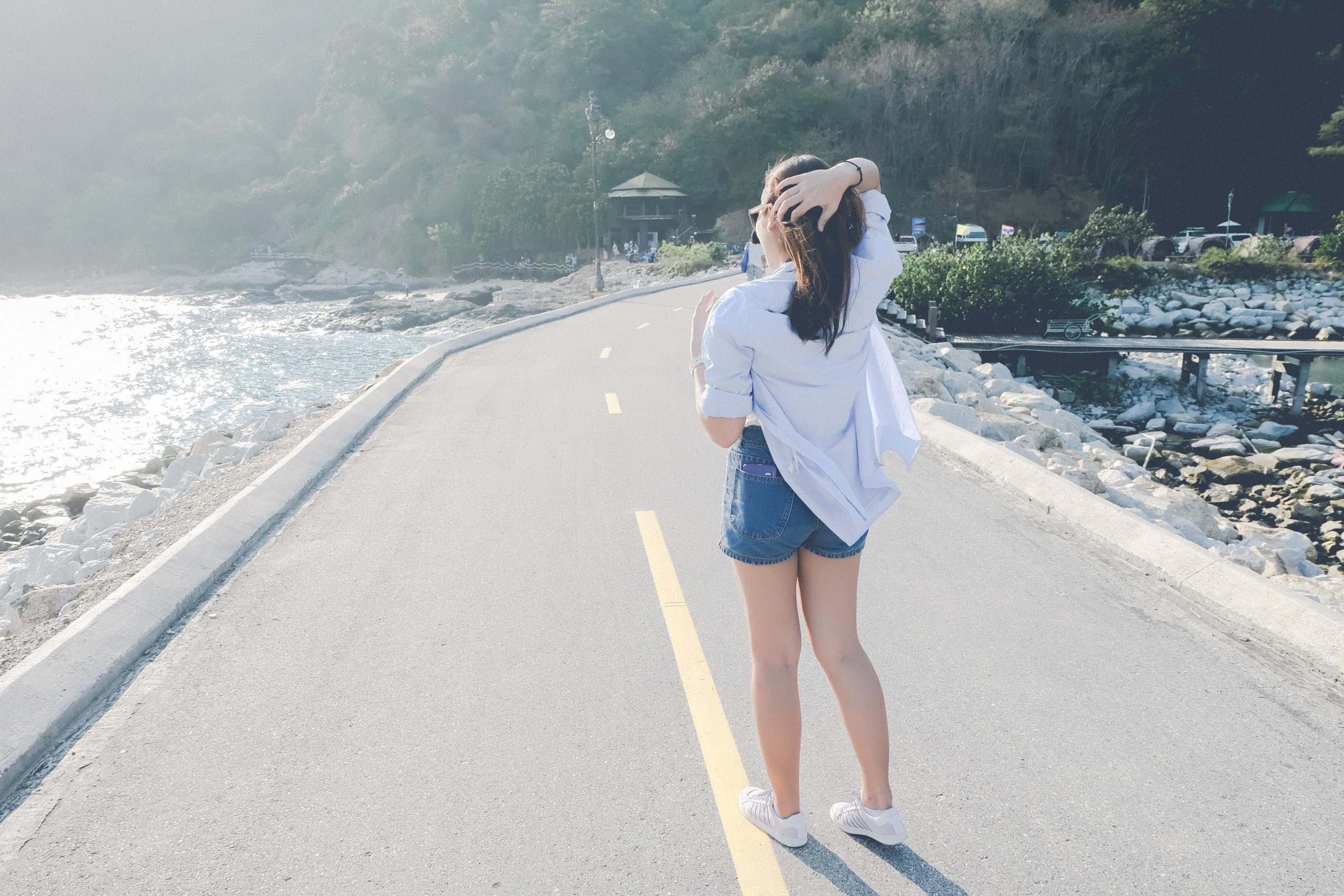 rear-view-young-woman-standing-road-by-sea